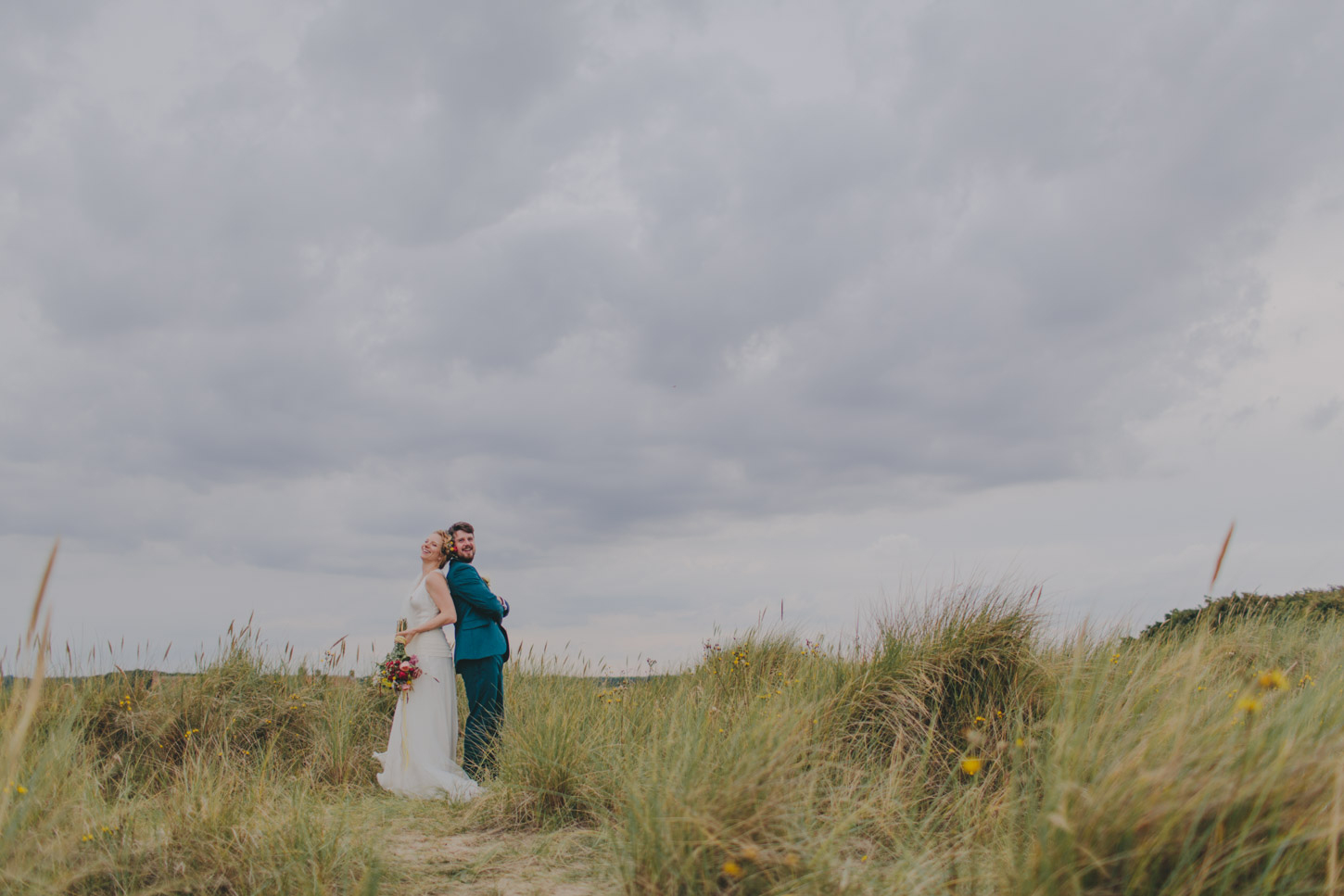 photograph of bride and groom having fun in Norfolk  Dunes